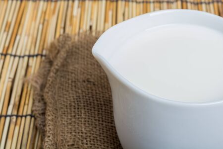 Cow milk and ceramic jug on wooden tableの写真素材