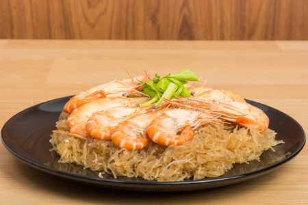 baked vermicelli with shrimp in black dish on wooden backgroundの写真素材
