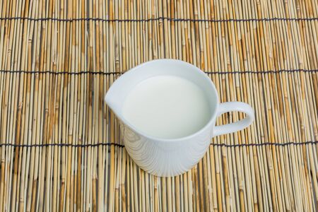 Cow milk and ceramic jug on wooden tableの写真素材