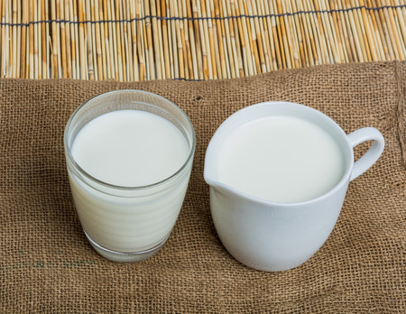 Cow milk and ceramic jug on wooden tableの写真素材