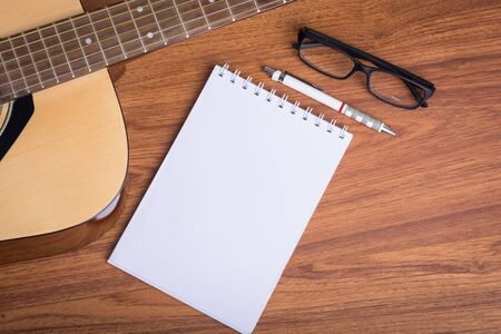 guitar notebook, pencil and eyeglasses on wooden backgroundの写真素材