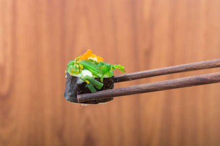 Sushi roll with black chopsticks on wooden backgroundの写真素材