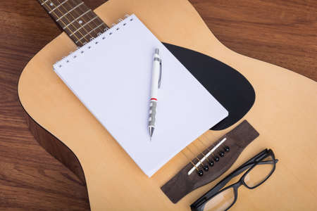 guitar notebook, pencil and eyeglasses on wooden backgroundの写真素材