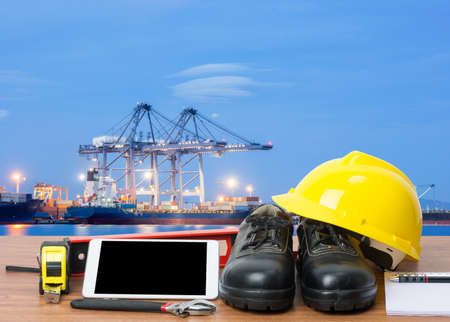 Working table engineer with tablet and tools in cargo port with craneの写真素材
