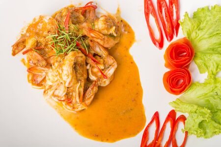 Curry fried shrimps and cooked rice in white dish closeup on table with wooden backgroundの写真素材