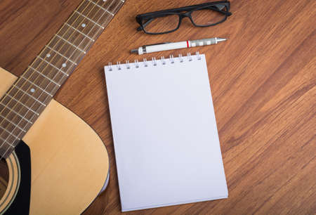 guitar notebook, pencil and eyeglasses on wooden backgroundの写真素材