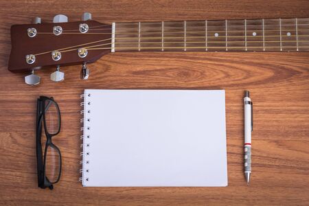 guitar notebook, pencil and eyeglasses on wooden backgroundの写真素材