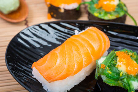 sushi in black dish on wooden backgroundの写真素材