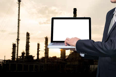 Engineering working hold conputer notebook in front of oil refinery power stationの写真素材