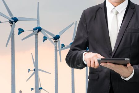 Engineering working hold tablet in front of Wind turbine power generatorの写真素材