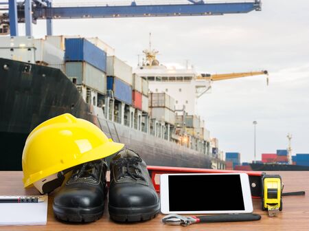 Working table engineer with tablet and tools in cargo port with craneの写真素材