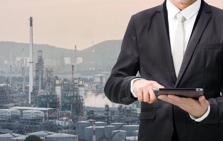 Engineering working hold tablet in front of oil refinery power stationの写真素材
