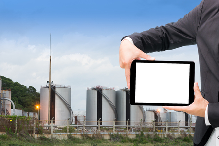 Engineering working hold tablet in front of oil refinery power stationの写真素材