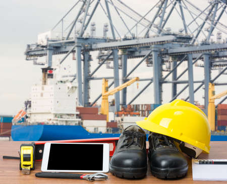 Working table engineer with tablet and tools in cargo port with craneの写真素材