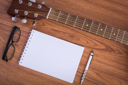 guitar notebook, pencil and eyeglasses on wooden backgroundの写真素材
