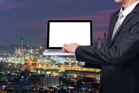 Engineering working hold conputer notebook in front of oil refinery power stationの写真素材