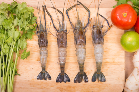 Raw tiger Fresh shrimps with vegetables Spicy Soup and herbs on wooden dark backgroundの写真素材