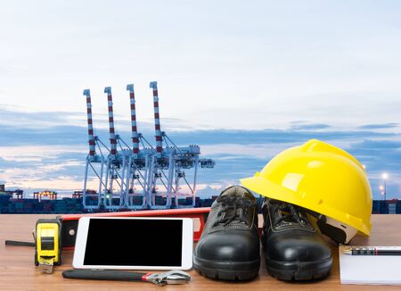 Working table engineer with tablet and tools in cargo port with craneの写真素材