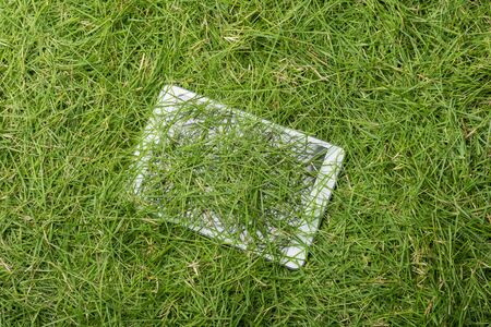 Tablet lying on the green grass texture backgroundの写真素材