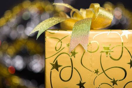 golden gift box with bow, bokeh glittery black backgroundの写真素材