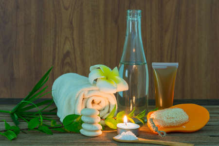 Spa still life with aromatic candles, Frangipani flowers and towel on wooden background