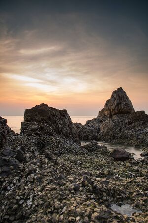 Landscape sunset and the sea waves impact rock on the beachの写真素材