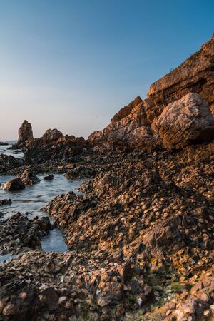 Landscape sunset and the sea waves impact rock on the beachの写真素材