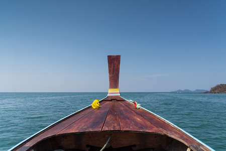 Thai wooden head longtail boat heads toward the tropical Andaman shores at Thailand andamanの写真素材