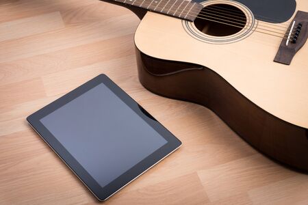 Acoustic guitar with digital tablet on the wooden tableの写真素材