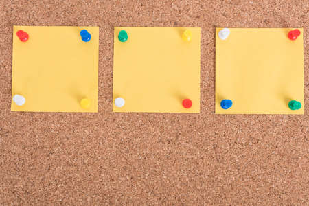 Yellow blank note papers with pin on wooden board background