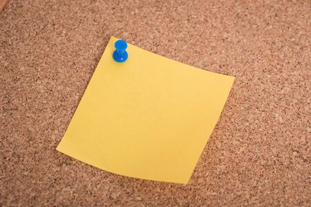 Yellow blank note papers with pin on wooden board background