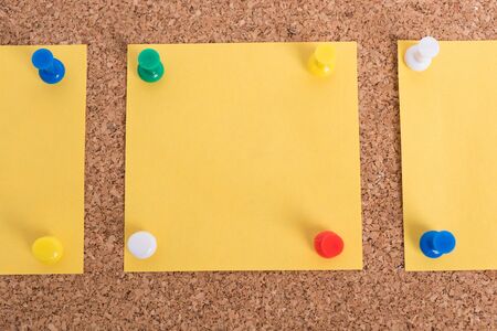 Yellow blank note papers with pin on wooden board backgroundの写真素材