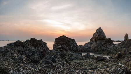 Landscape sunset and the sea waves impact rock on the beachの写真素材