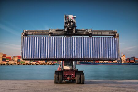 Forklift handling container box loading at port cargo at sunsetの写真素材