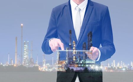 Double exposure of businessman hand hold tablet, oil refinery industry plant, Petroleum energy conceptの写真素材