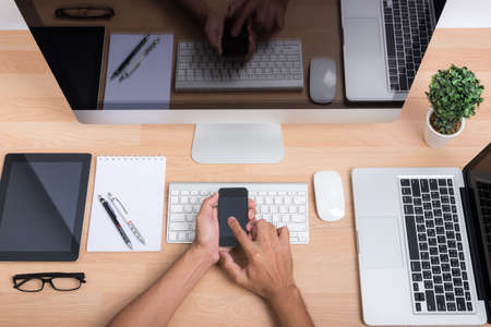 Top view hands of people working with mobile phone with computer PC, laptop,  digital tablet and smartphone on wooden desk workspaceの写真素材