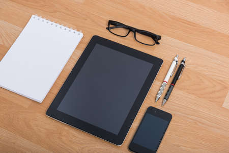 Top view office table with mobile phone, keyboard and mouse on wooden deskの写真素材