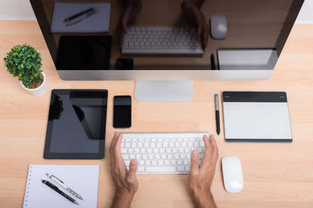 Top view office hand working on computer PC wite tablet, mobile phone, keyboard and mouse on wooden...