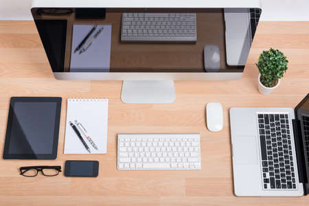 Top view computer PC, laptop with digital tablet and smartphone on wooden deskの写真素材