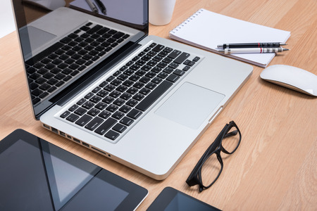 Top view open laptop with digital tablet and white smartphone on wooden deskの写真素材