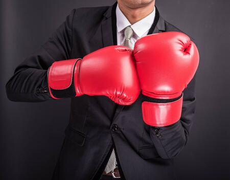 Young businessman with boxing gloves isolated on black backgroundの写真素材