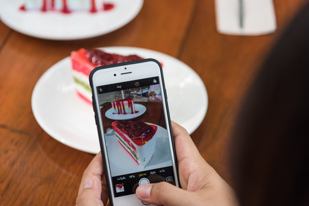 Taking photo of Sliced tasty strawberry cake on wooden table backgroundの写真素材
