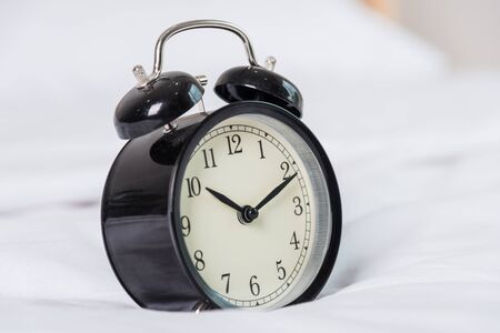 Black Alarm clock at 8 am on the bed. to wake up