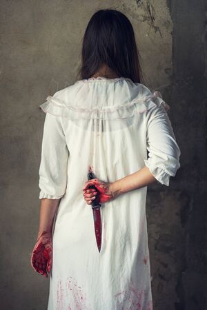 Woman holding knife back on her hand with blood, halloween conceptの写真素材