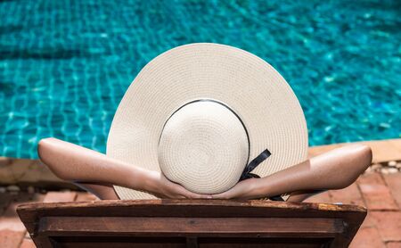 Asian young Woman in hat relaxing sleep at poolside blue waterの写真素材