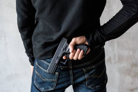 Back view man reaching hand gun attached, robbery, crime, kidnapping