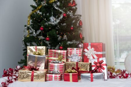 Many Christmas presents gift boxes on a table with Christmas tree, holidays, presents, new year and celebration conceptの写真素材