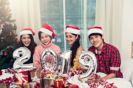 Group of friends celebrating Christmas at home and showing 2019 up, Christmas or New Year conceptの写真素材