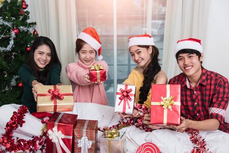 Group of friends celebrating showing gift box Christmas at homeの写真素材