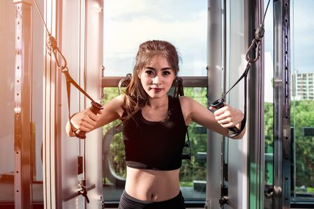 Beautiful fit woman works out with machine in fitness gym